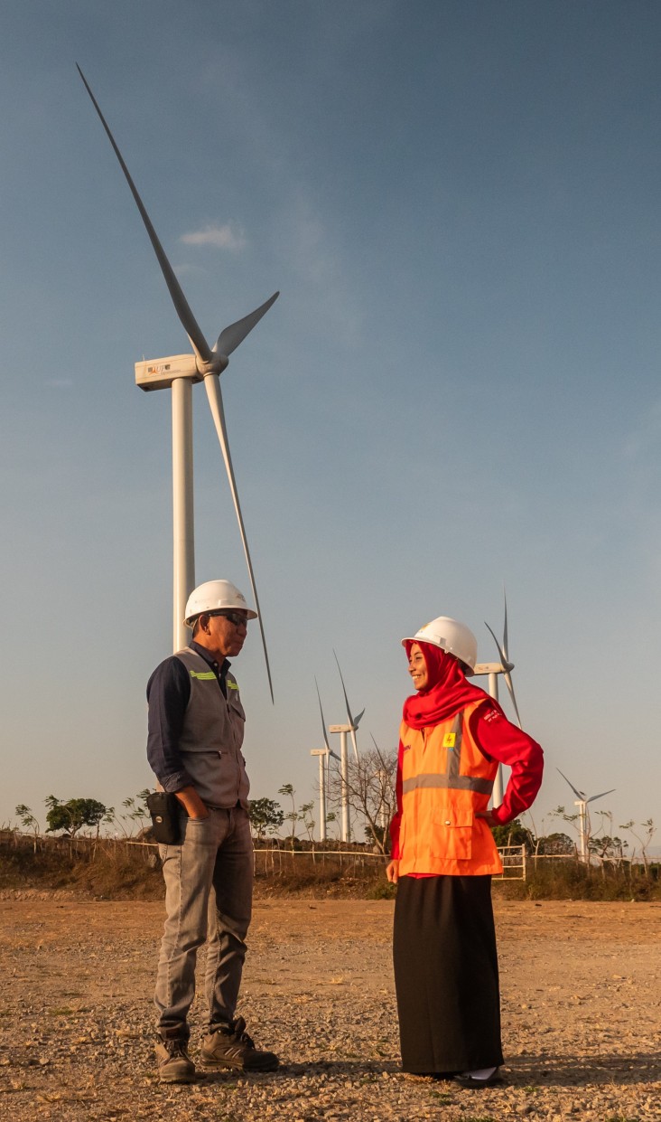 In front of a wind turbine in Tolo, South Sulawesi, two staff members of Indonesia's energy utility company exchange ideas. Since 2015, USAID has supported the generation of 438 megawatts of renewable, providing clean energy access to more than 3.3 million people.