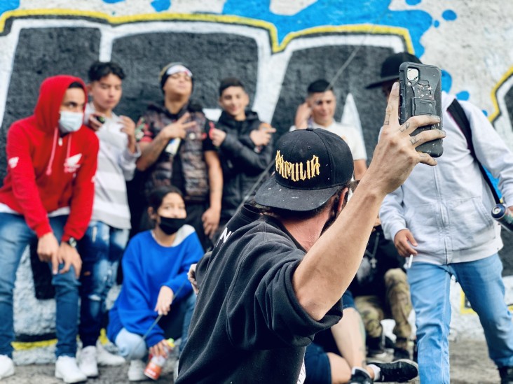 A group poses in front of a mural.