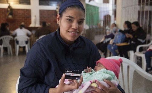 A beneficiary of USAID/BHA-funded MPCA programming in Peru shows off the prepaid debit card she will use to pay for basic household items.