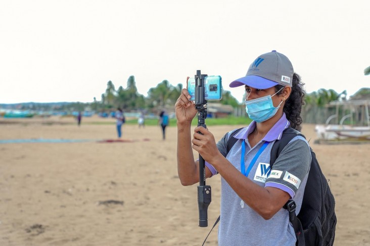 Sign language reporter Suranga Udari takes photos with her iPhone on a beach in southern Sri Lanka.