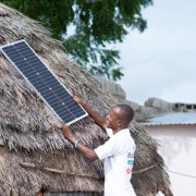 Un agent de Baobab Plus pose un panneau solaire sur une maison