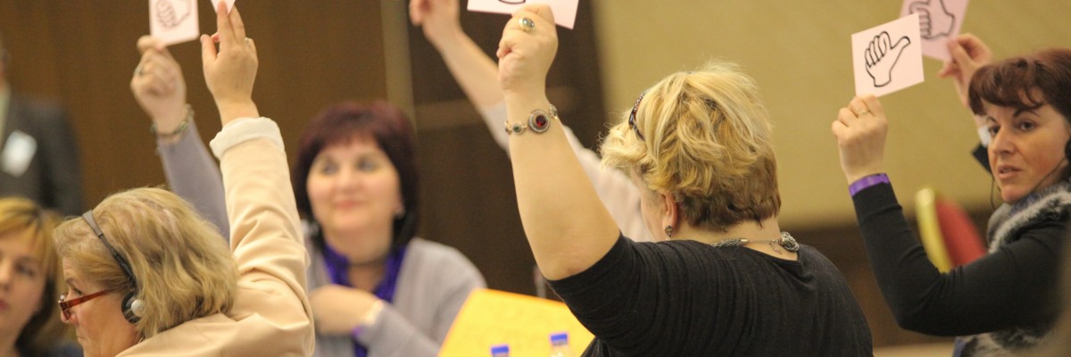 A group of women hold thumbs up and thumbs down signs