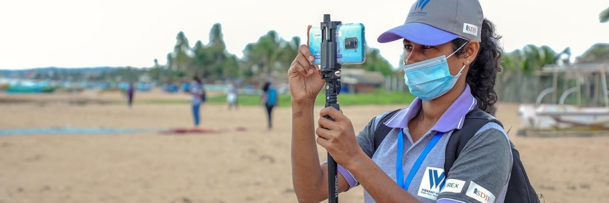 Sign language reporter Suranga Udari takes photos with her iPhone on a beach in southern Sri Lanka.