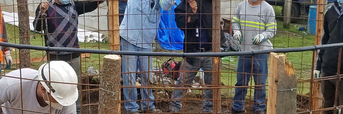 Seven persons work on building a fence